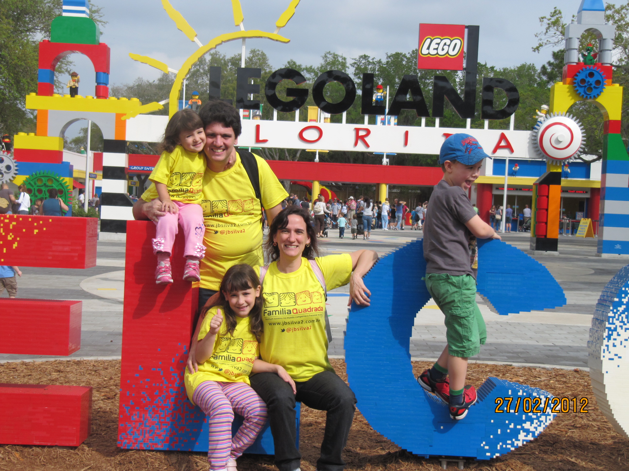 Família reunida no letreiro Welcome da Legoland